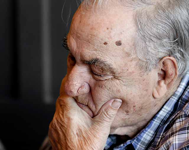 senior man holding jaw wincing